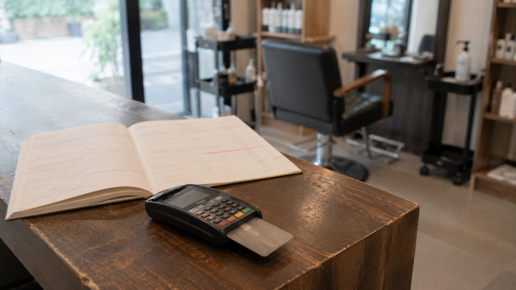 เครื่องรับชำระบัตรและสมุดนัดหมายบนเคาน์เตอร์ร้านเสริมสวยสำหรับยืนยันคิวด้วยมัดจำ